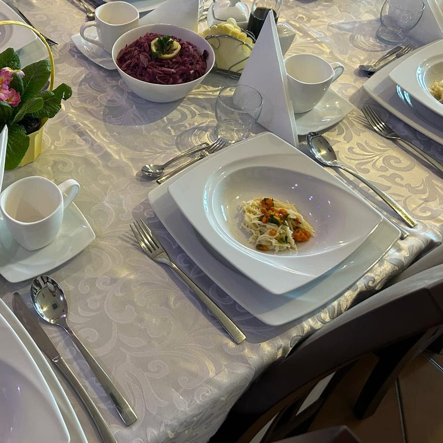 Stół nakryty w sali bistro: talerz z przystawką, sztućce, filiżanka